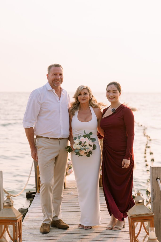 A married couple and a wedding celebrant on the jetty at the beach